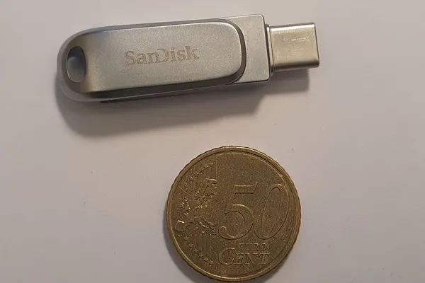 Chiavetta USB USB-C appoggiata su un tavolo accanto a una moneta, close up della memoria flash che il computer non riconosce più