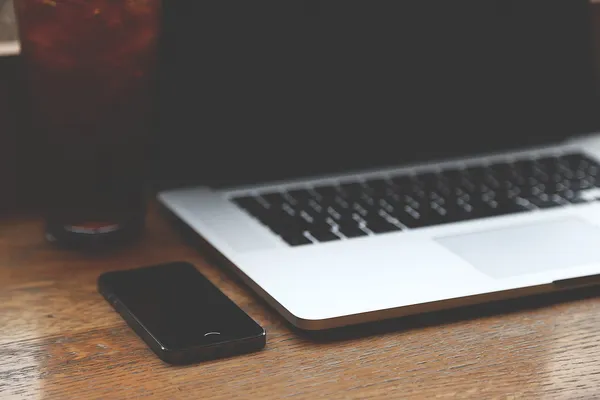 Portatile e smartphone su un tavolo di legno durante la diagnosi di un computer diventato lento