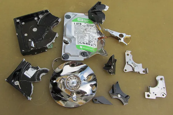Hard disk rotto smontato con testine e piatti danneggiati, come arriva in laboratorio per il recupero dati