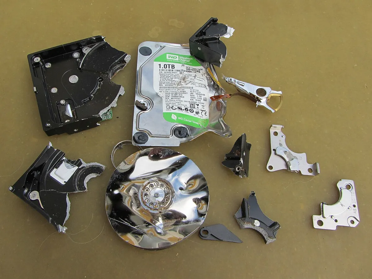 Hard disk rotto smontato con testine e piatti danneggiati, come arriva in laboratorio per il recupero dati