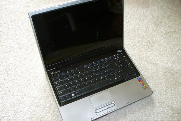 Computer portatile datato appoggiato su un tappeto, il PC con Windows arrivato a fine supporto da valutare