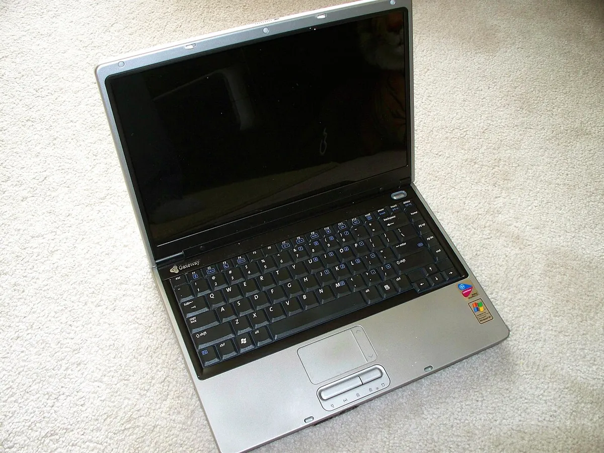 Computer portatile datato appoggiato su un tappeto, il PC con Windows arrivato a fine supporto da valutare